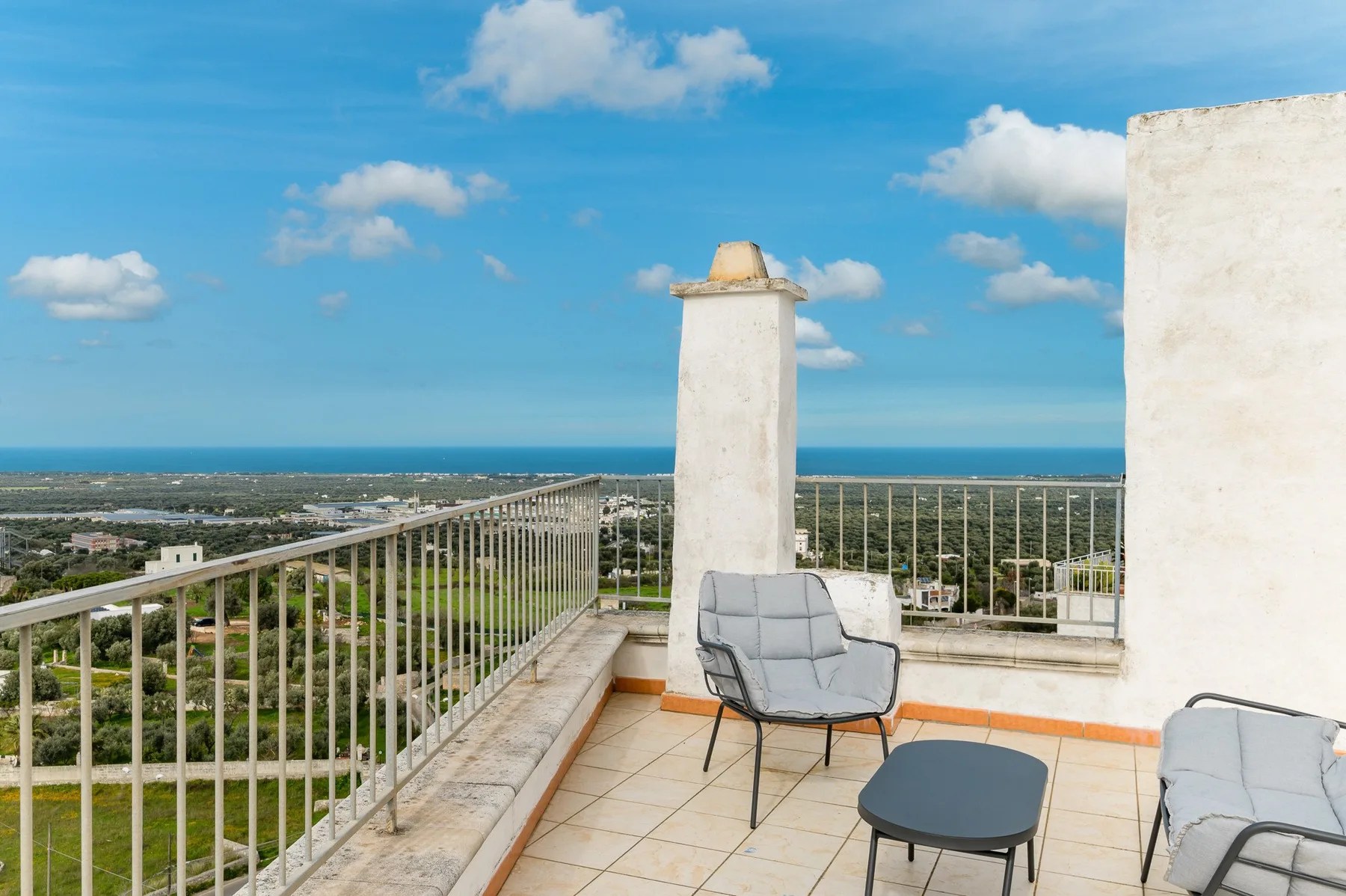 Una terraza en la azotea con asientos al aire libre tiene vistas a un paisaje costero.