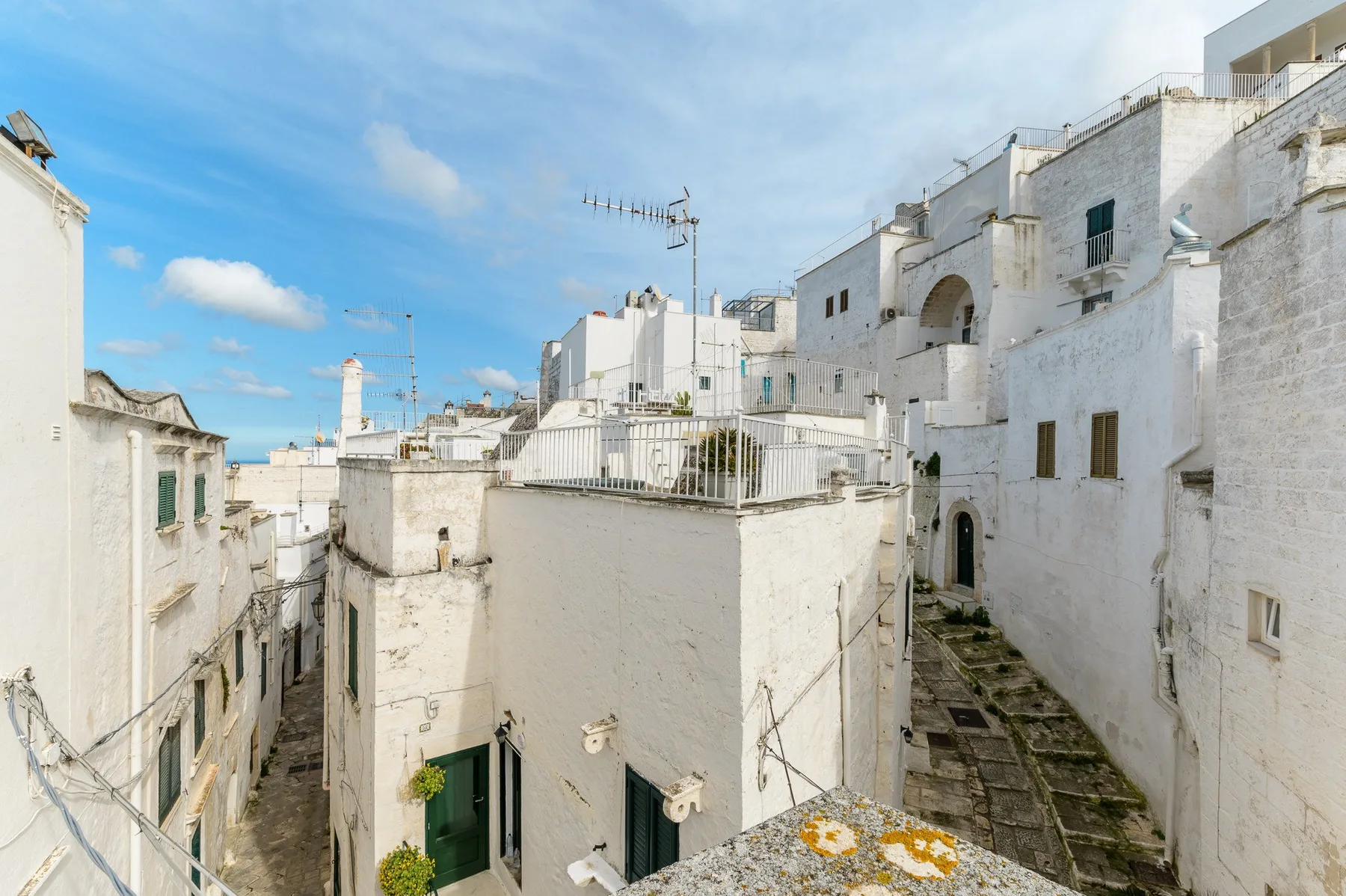 Edificios blancos bordean una estrecha calle de piedra bajo un cielo azul despejado.