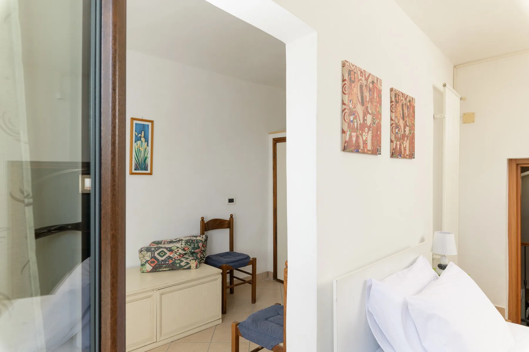 Un dormitorio con una cama blanca junto a una zona de estar contigua.
