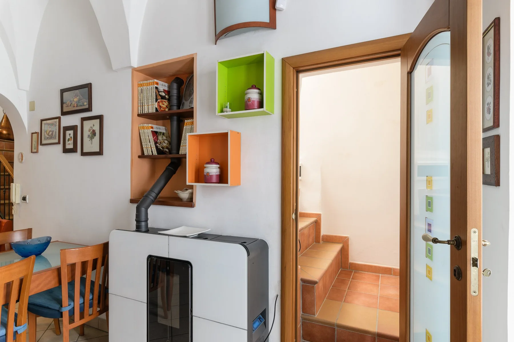 Un comedor con asientos de madera está junto a una estufa y una puerta abierta.