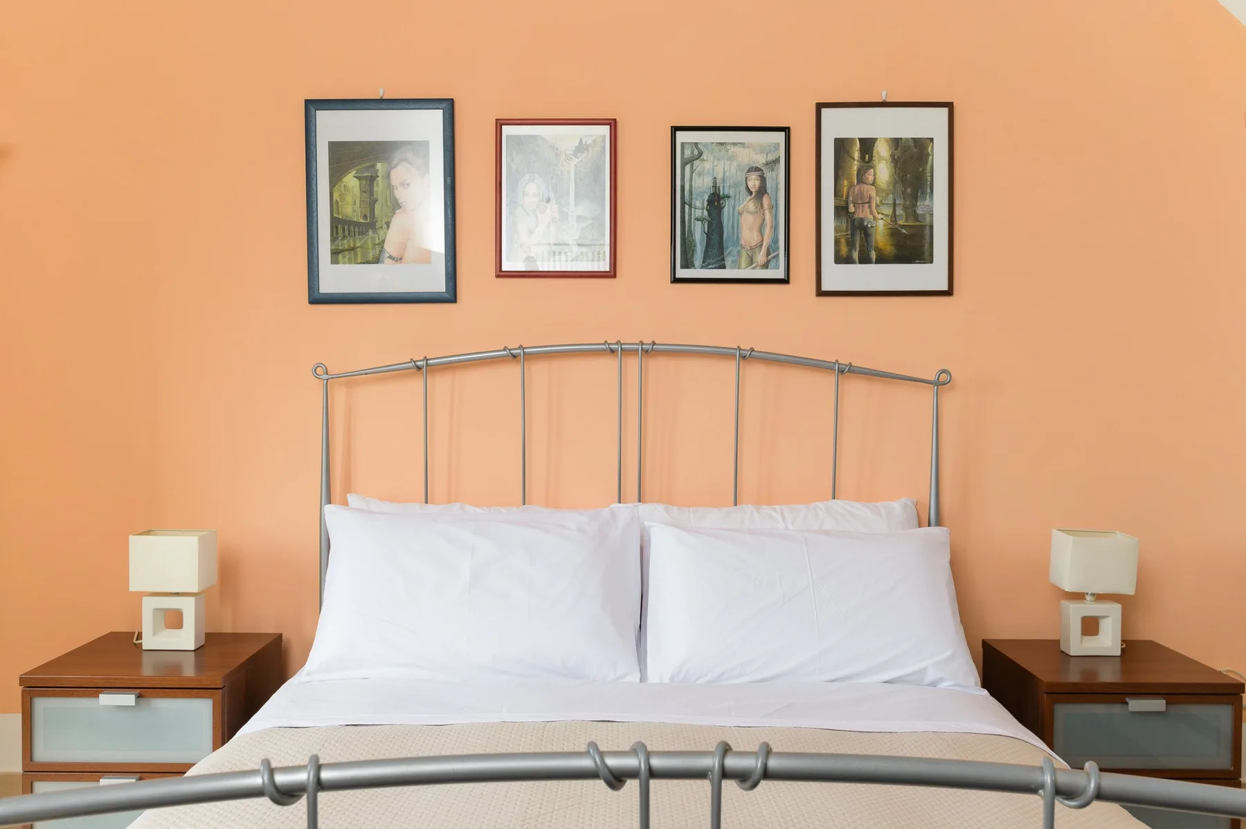 Un dormitorio con una cama bien arreglada contra una pared naranja.