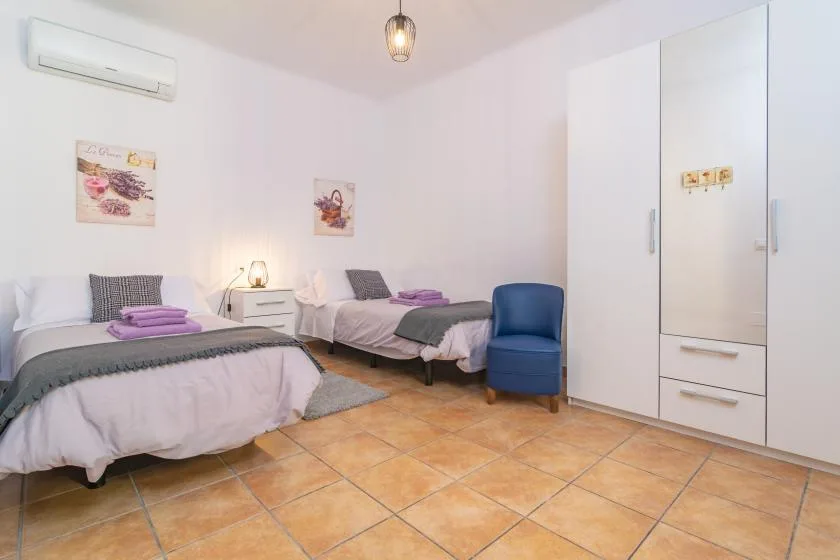 Un dormitorio con dos camas, una mesita de noche y una silla azul.