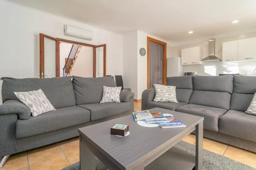 Una sala de estar con asientos grises, una mesa de centro y una cocina abierta.