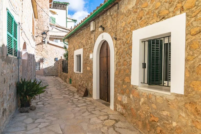 Un callejón estrecho empedrado pasa entre edificios de piedra con ventanas con contraventanas.