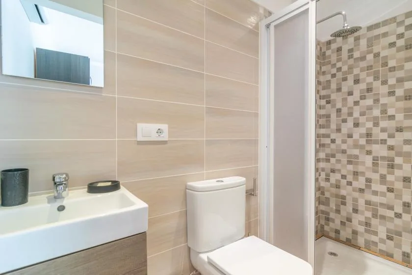 Un baño con lavabo, inodoro y zona de ducha con azulejos.