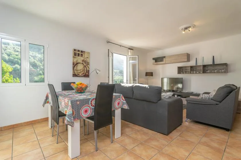 Una luminosa sala de estar y comedor con mesa, asientos y ventanas.