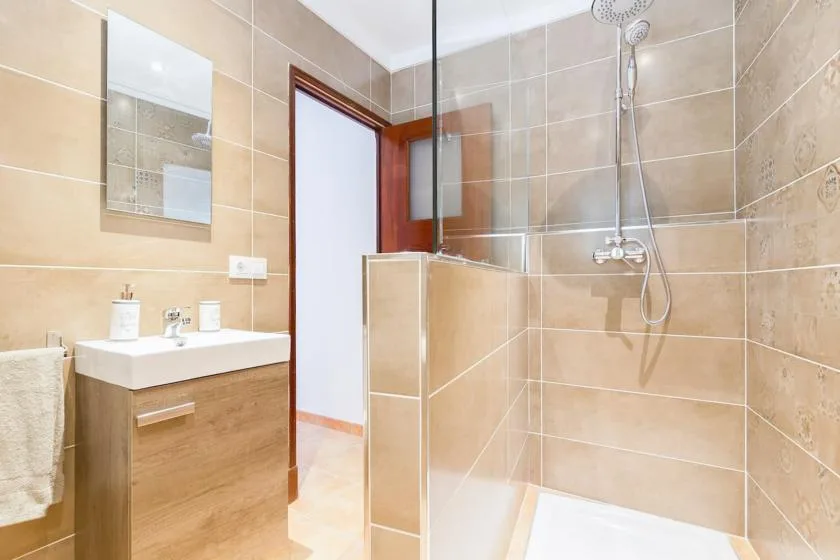 Un baño con azulejos, lavabo y ducha con mampara de vidrio.