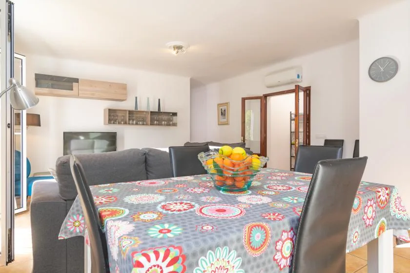 Una luminosa sala de estar y comedor tiene un mantel estampado y asientos alrededor de la mesa.