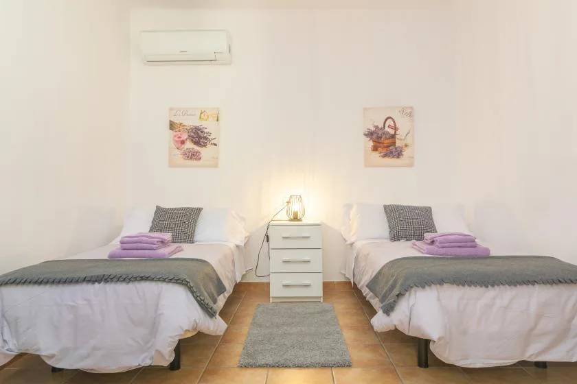 Un dormitorio con dos camas y una mesita de noche entre ellas.