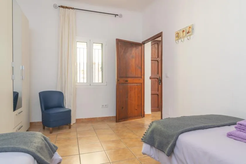 Un dormitorio con camas, una ventana y una puerta de madera abierta.
