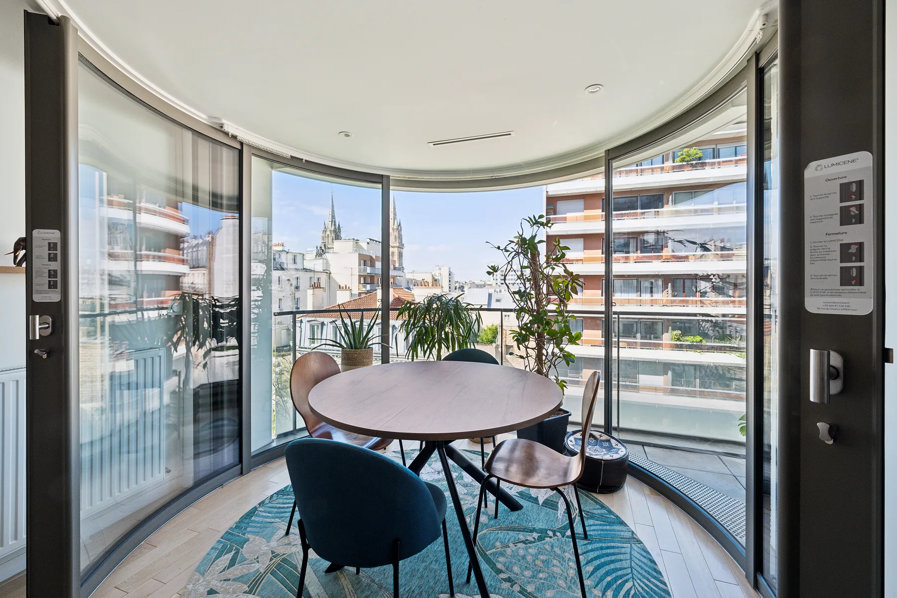 Comedor acristalado y curvo con una mesa redonda y vistas a la ciudad.