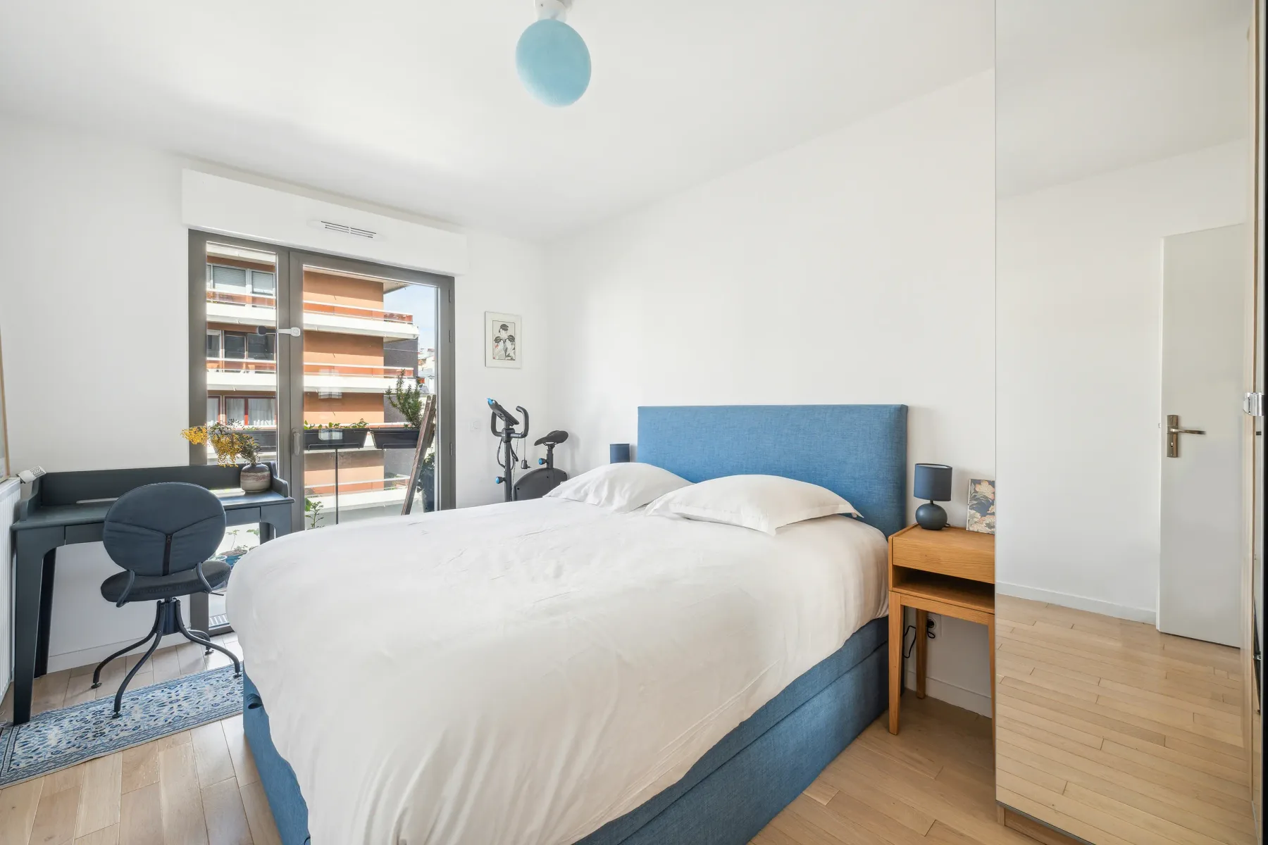 Un dormitorio luminoso con una cama junto a una ventana y un escritorio.