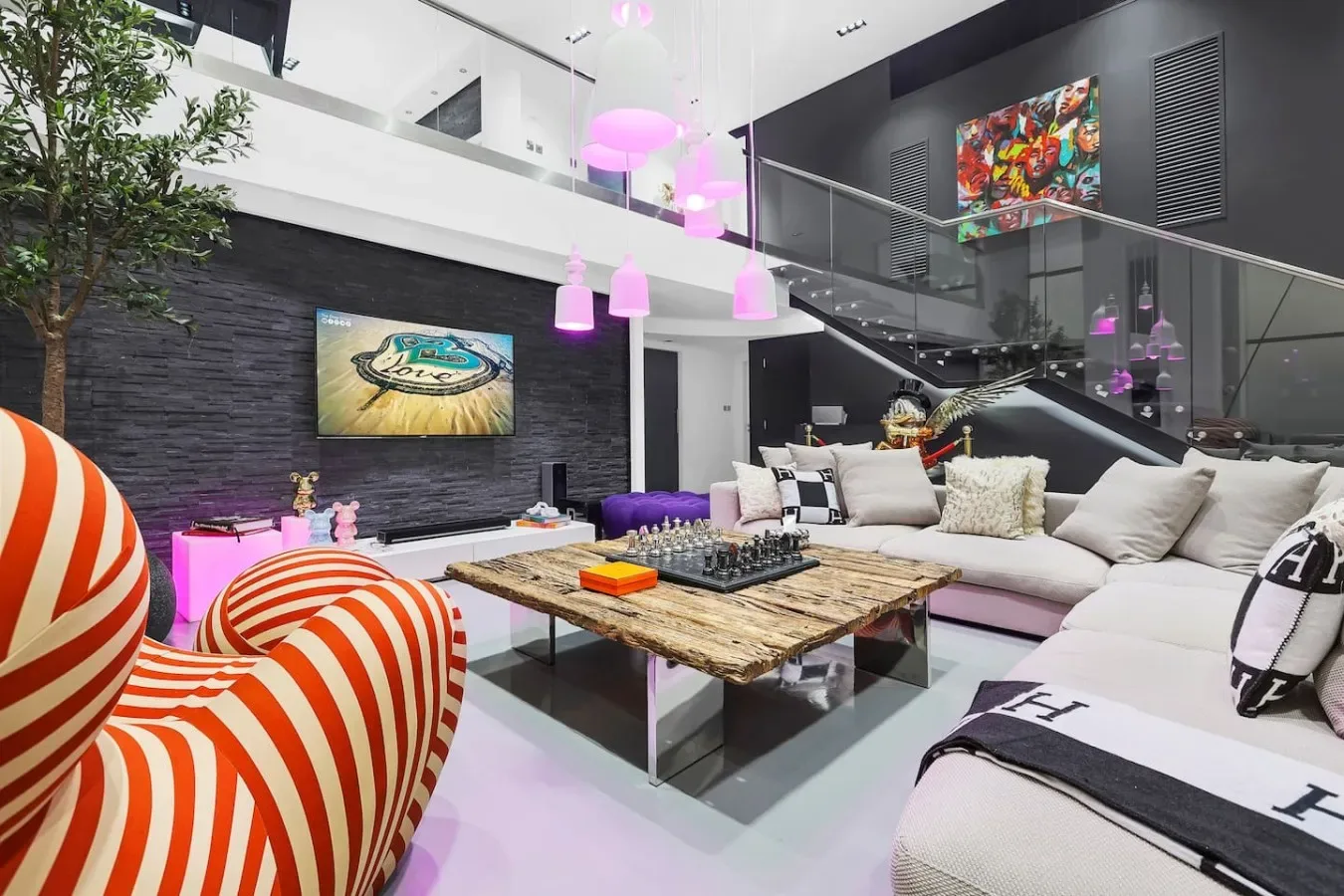 Una sala de estar moderna con asientos seccionales, una mesa baja y lámparas colgantes de colores.