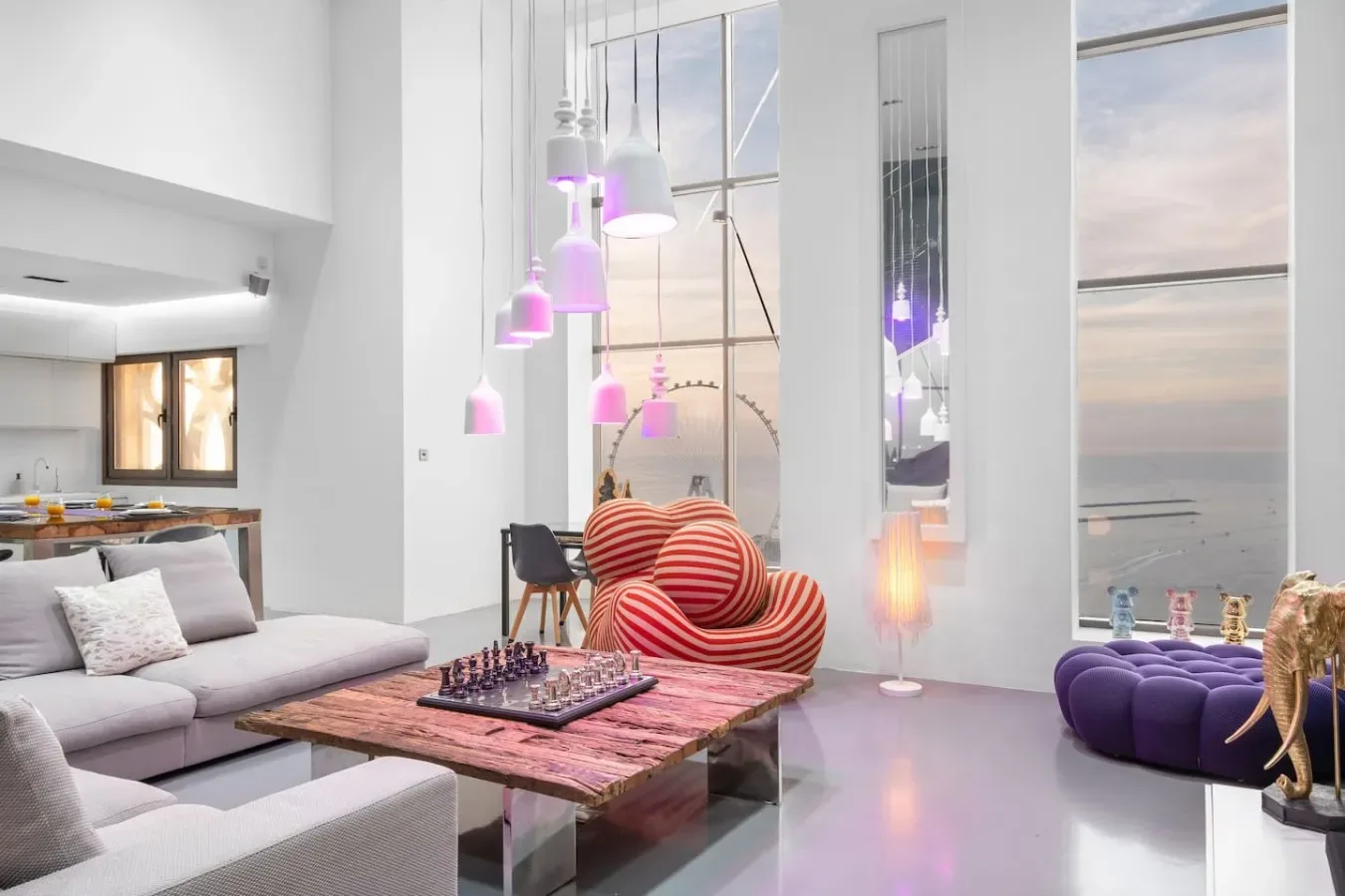Una sala luminosa con una mesa baja, asientos y lámparas colgantes de colores.