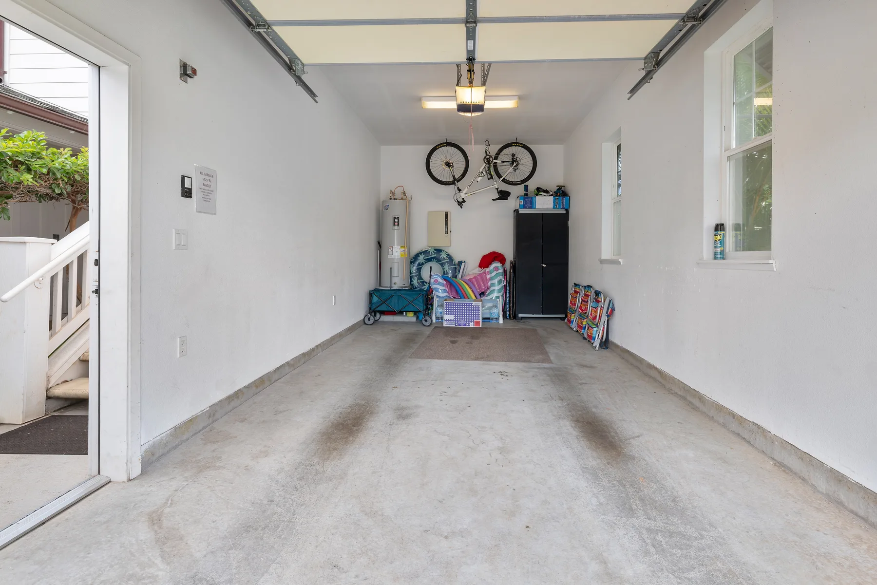 Un garaje con bicicletas y artículos domésticos guardados junto a la pared del fondo.