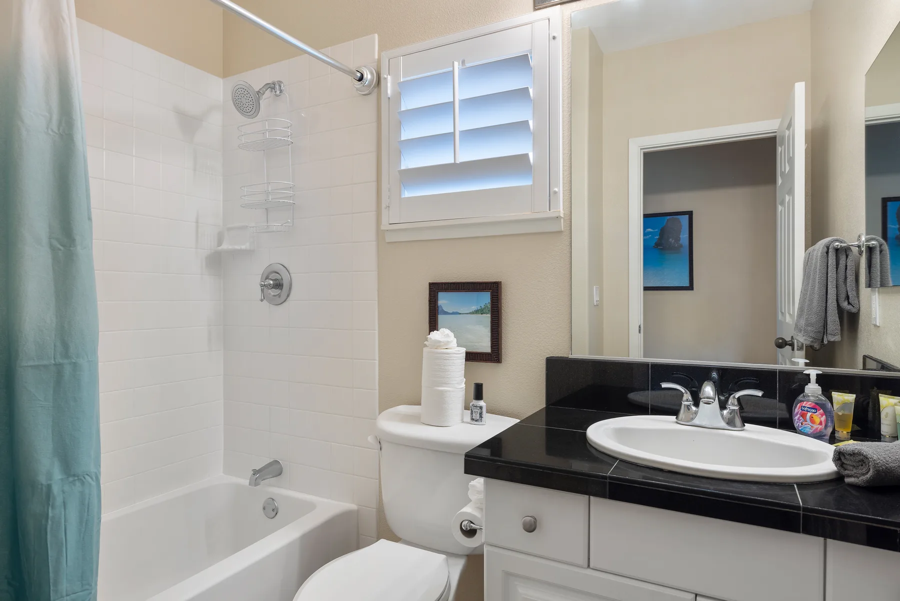 Un baño con bañera, ducha y lavabo bajo una ventana.