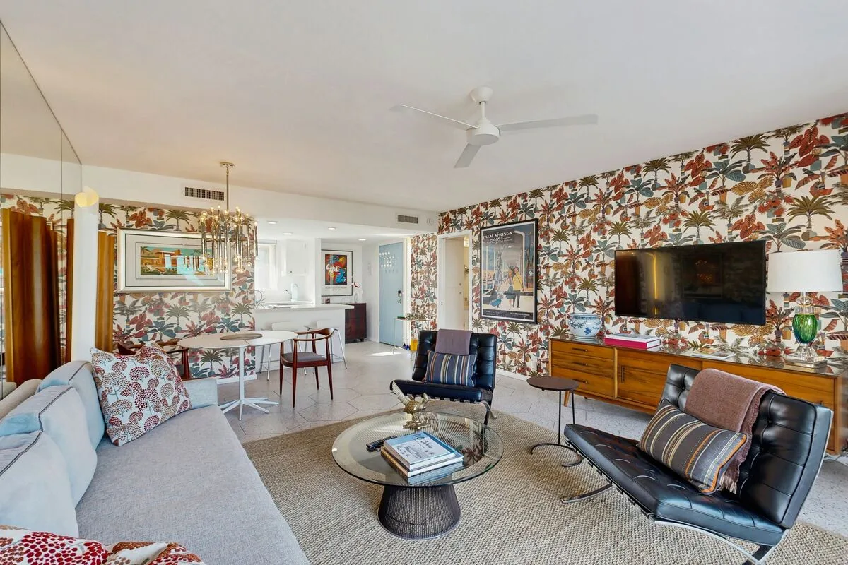 A living room with seating, a coffee table, and patterned wallpaper.