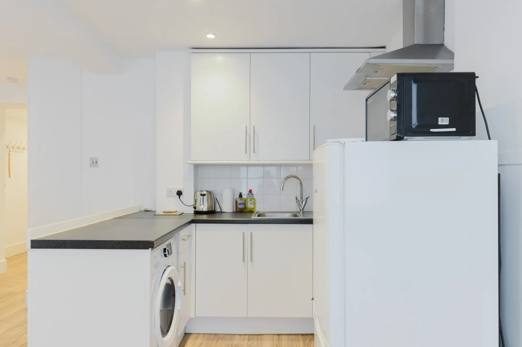 A compact kitchen with white cabinets and a countertop sink.