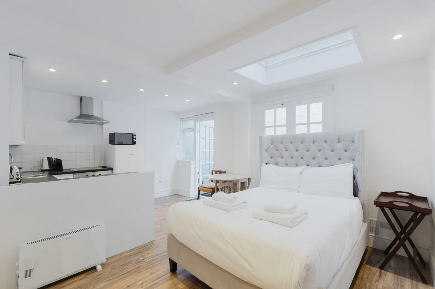A bright bedroom with a bed beside a compact kitchen.