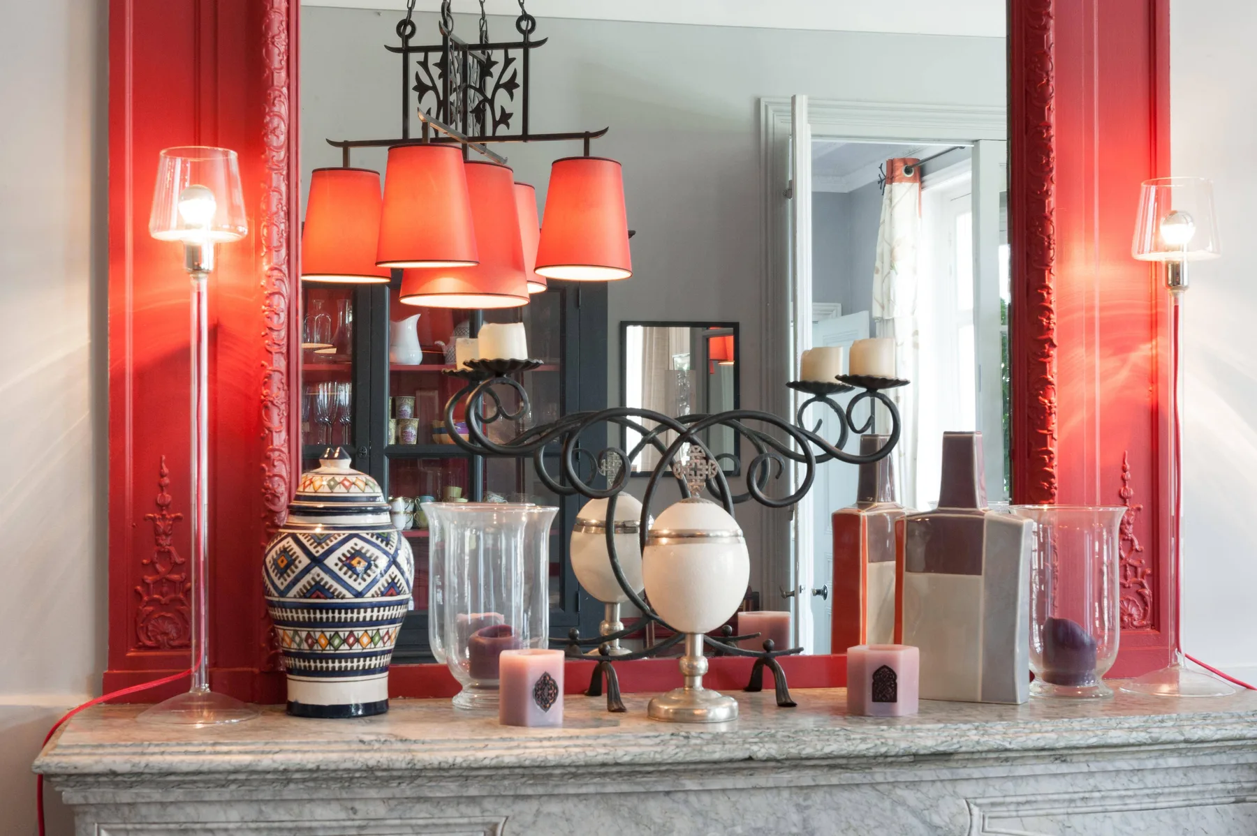 A decorative console displays lamps, glass vessels, and a patterned ceramic vase.
