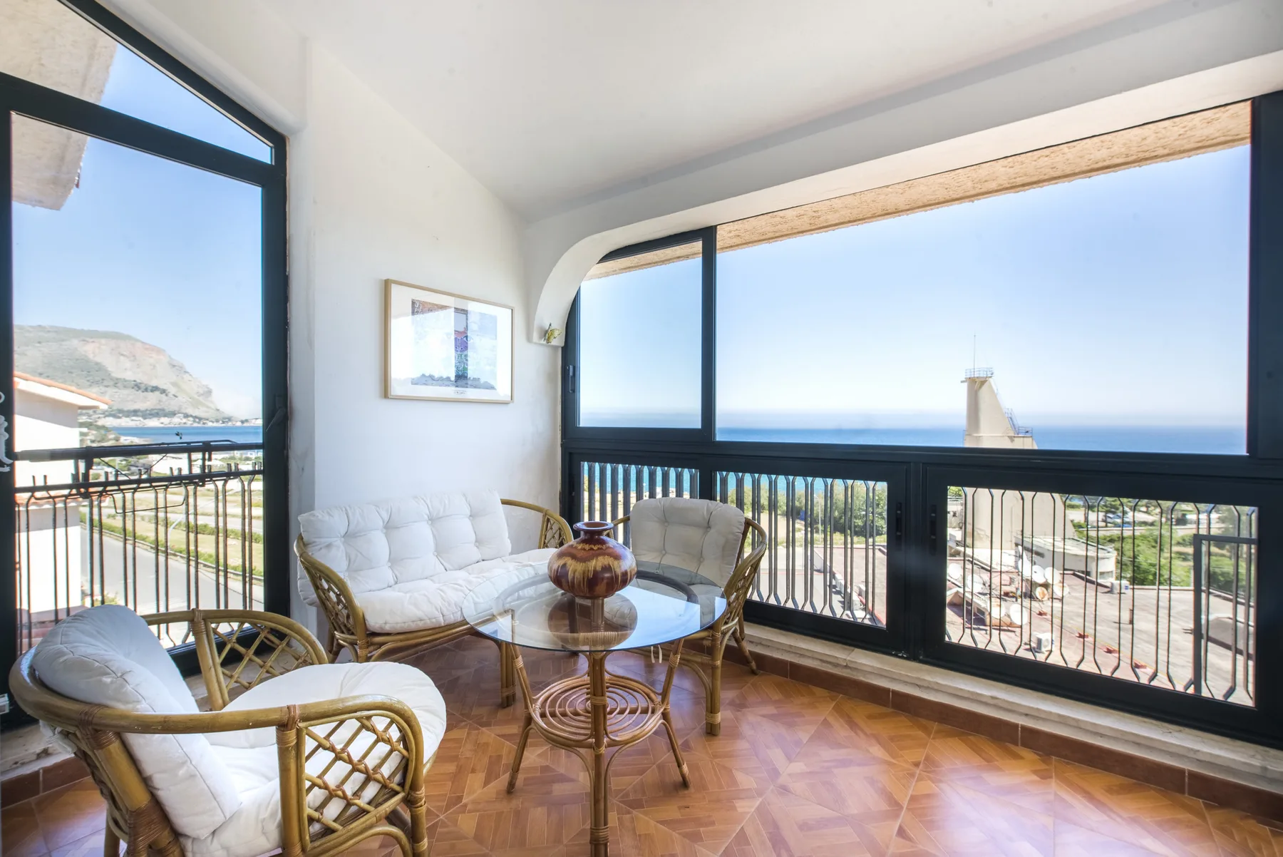 Una zona de estar soleada con asientos de mimbre y amplias ventanas con vistas al mar.