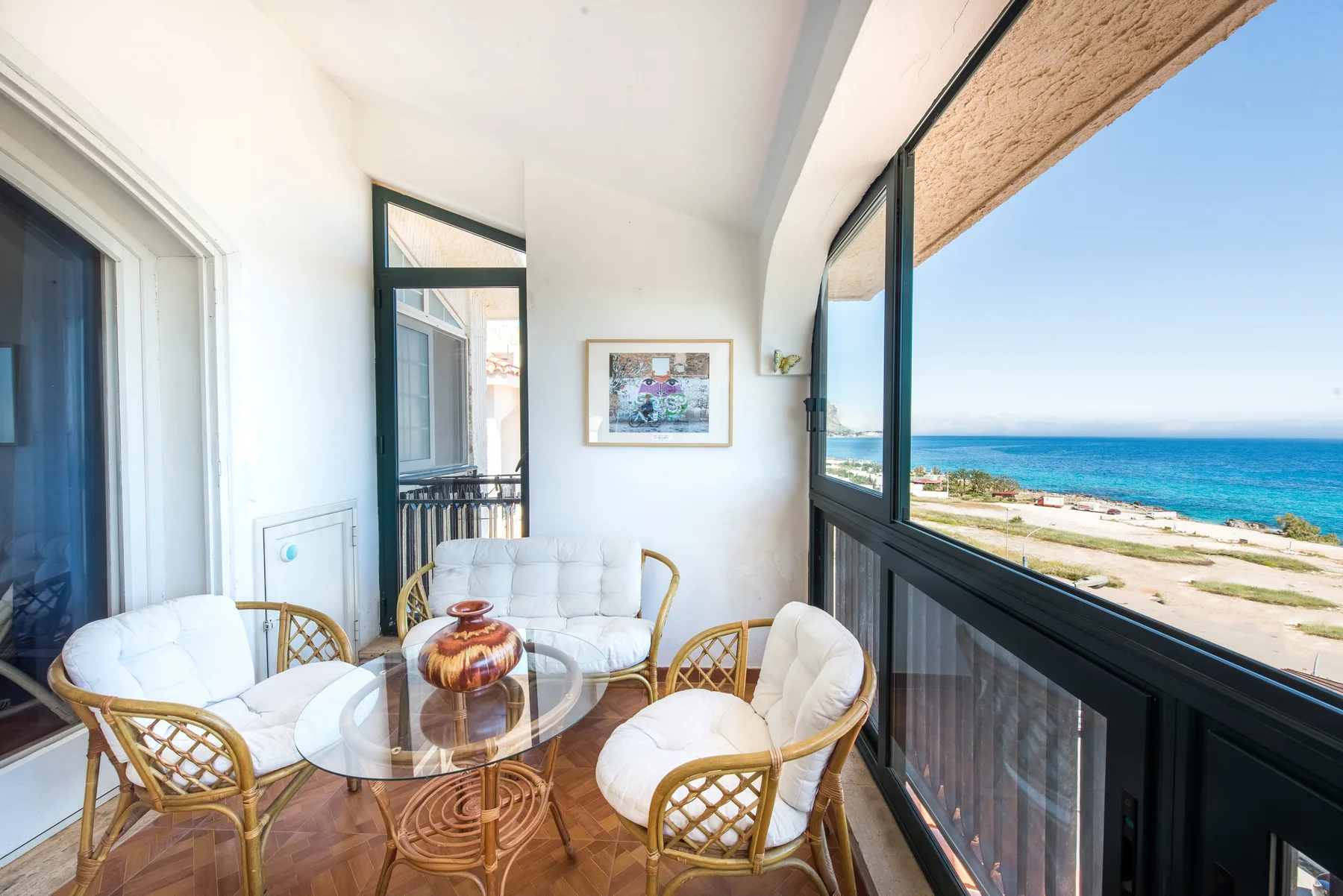 Una luminosa zona de estar con asientos de mimbre junto a grandes ventanas con vistas al mar.
