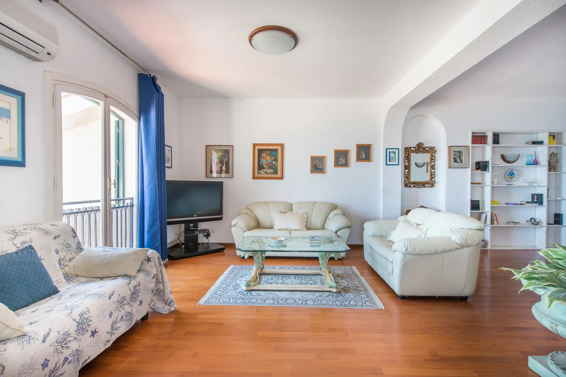 Una luminosa sala de estar con asientos alrededor de una mesa de centro y un televisor.