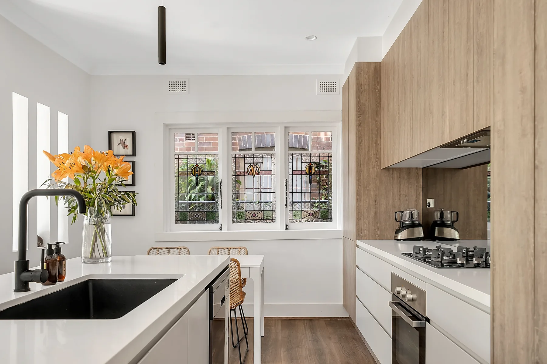Una cocina luminosa con encimeras blancas y ventanas grandes.