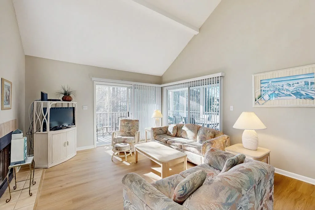 A bright living room with seating, a coffee table, and large windows.