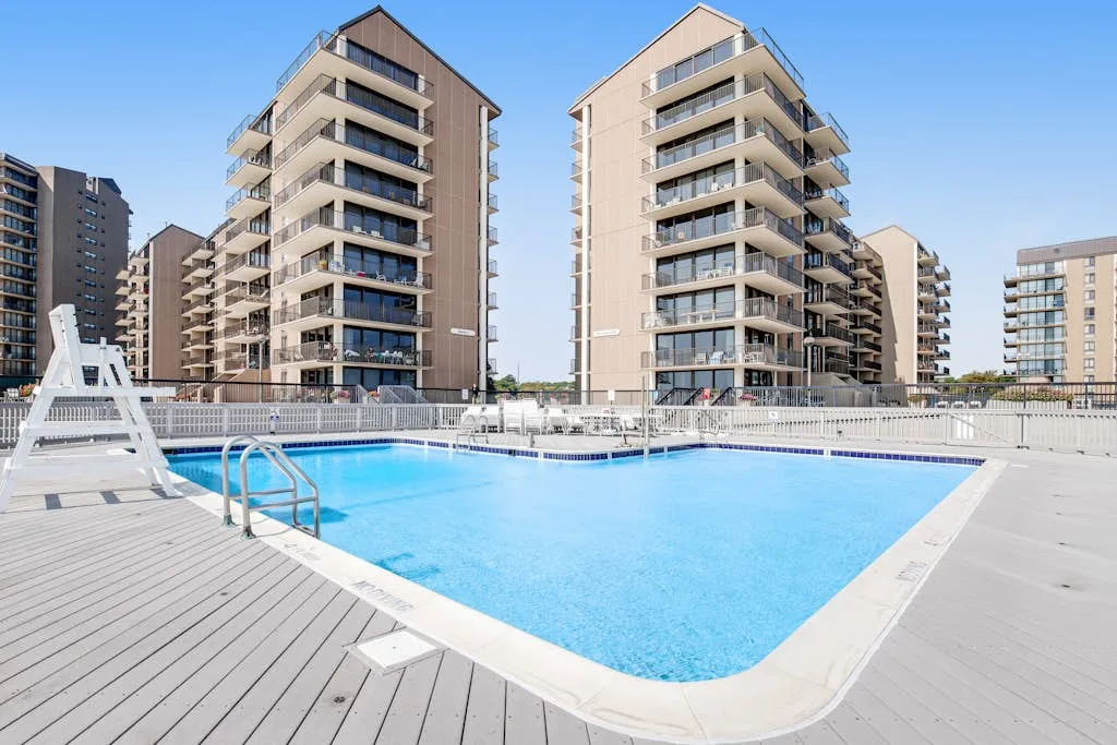 An outdoor swimming pool sits beside several tall apartment buildings.