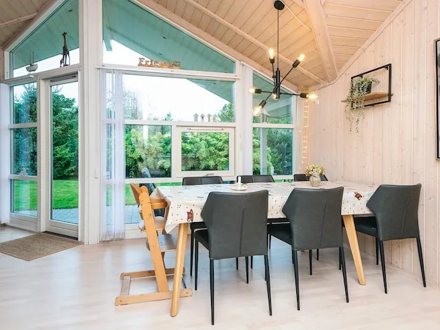 A bright dining area with a table and chairs beside large windows.