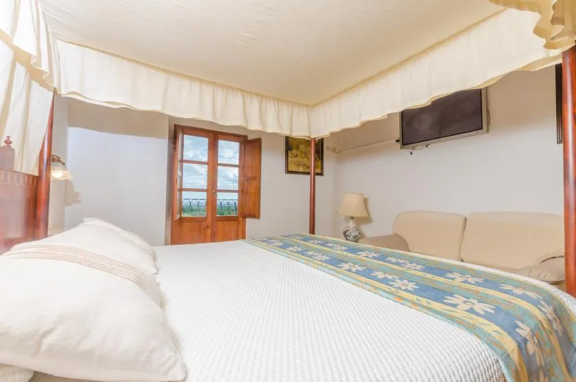 Un dormitorio con una cama, una puerta de madera y un televisor en la pared.