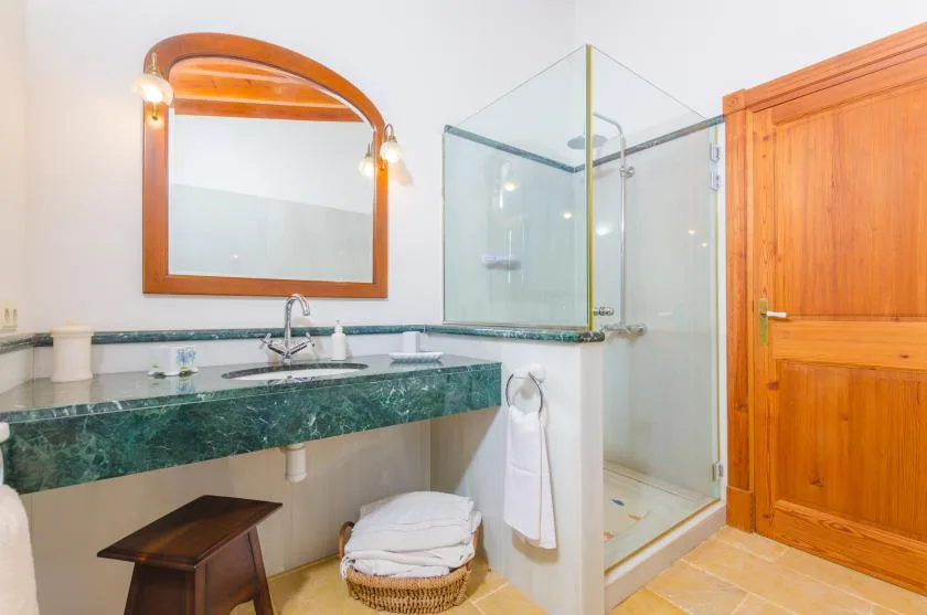Un baño con una encimera verde, lavabo y ducha de vidrio.
