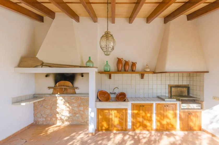 Una cocina rústica con una gran chimenea, un salpicadero de azulejos y gabinetes de madera.