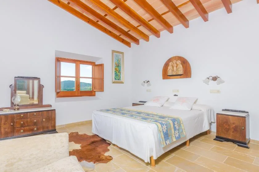 Un dormitorio con una cama bajo vigas de madera a la vista.