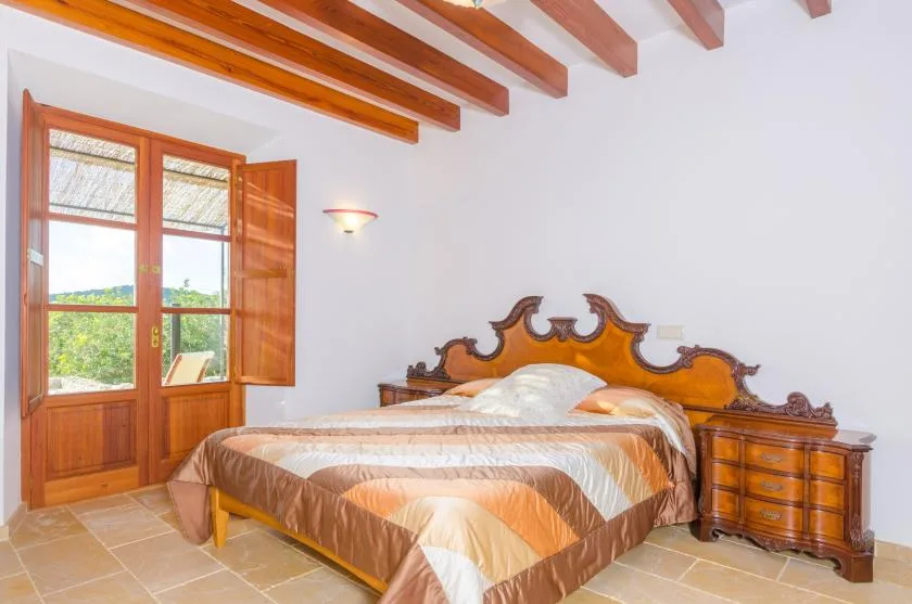 Un dormitorio con una cama, una ventana de madera y vigas expuestas en el techo.