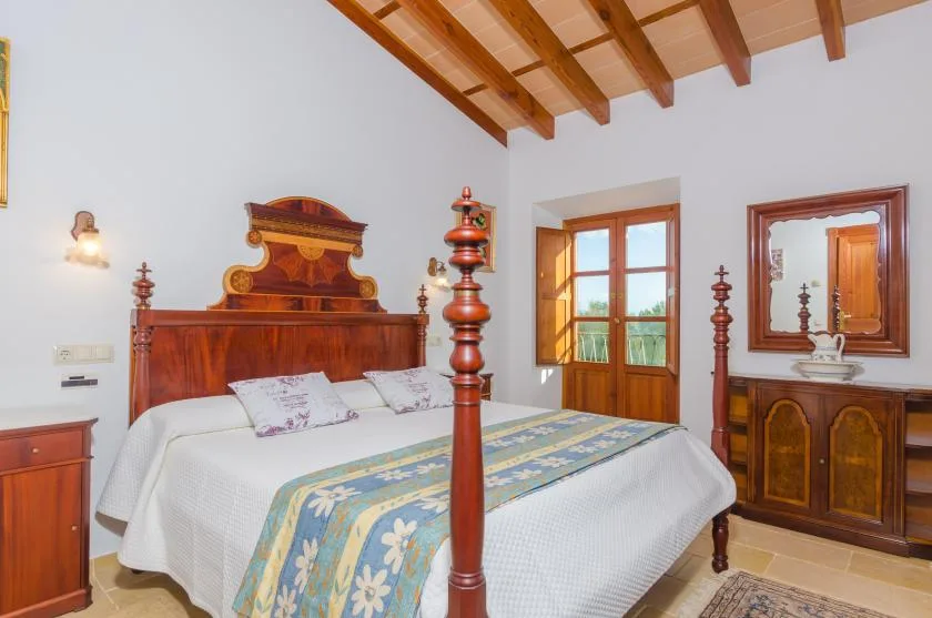 Un dormitorio con una cama de madera, ropa de cama estampada y vigas de madera en el techo.