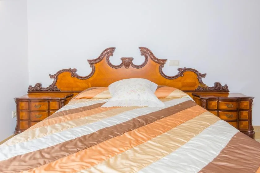 Un dormitorio con una cama vestida con ropa de cama a rayas y un cabecero de madera ornamentado.