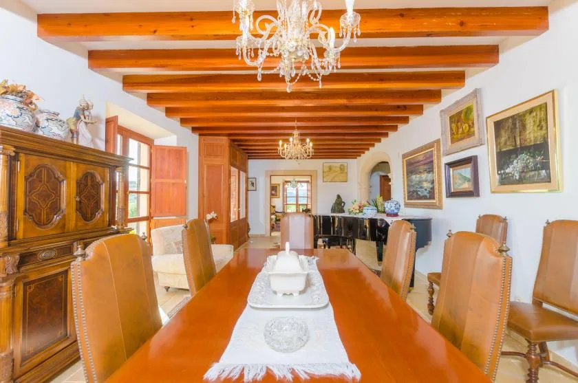 Un comedor con una mesa larga de madera bajo vigas expuestas.