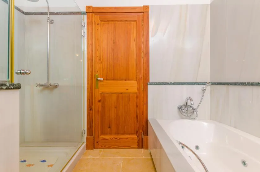 Un baño con ducha de vidrio, puerta de madera y bañera.