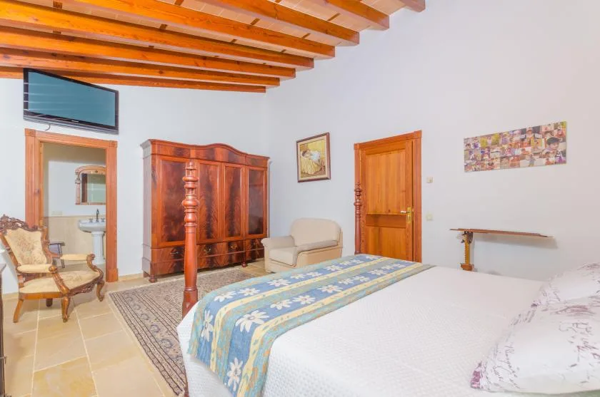 Un dormitorio con una cama grande, un armario de madera y vigas de techo a la vista.