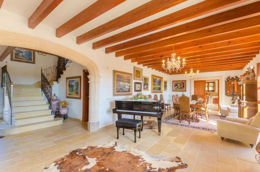 Amplia sala de estar y comedor con vigas de madera expuestas y un piano.