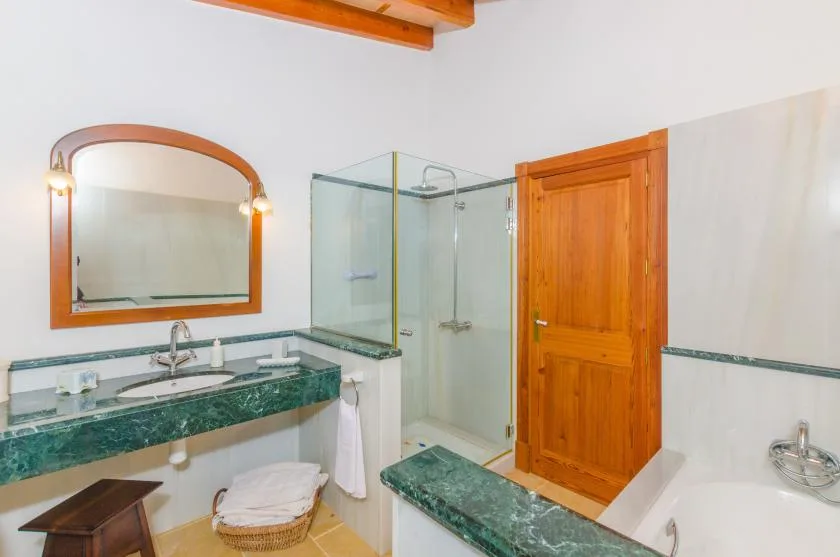 Un baño luminoso con encimera verde, espejo y ducha de vidrio.