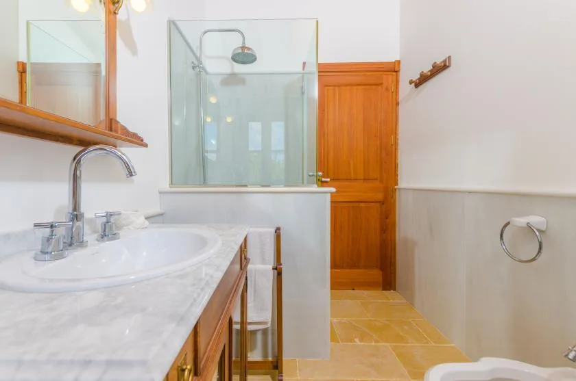 Un baño con lavabo, ducha de vidrio y puerta de madera.