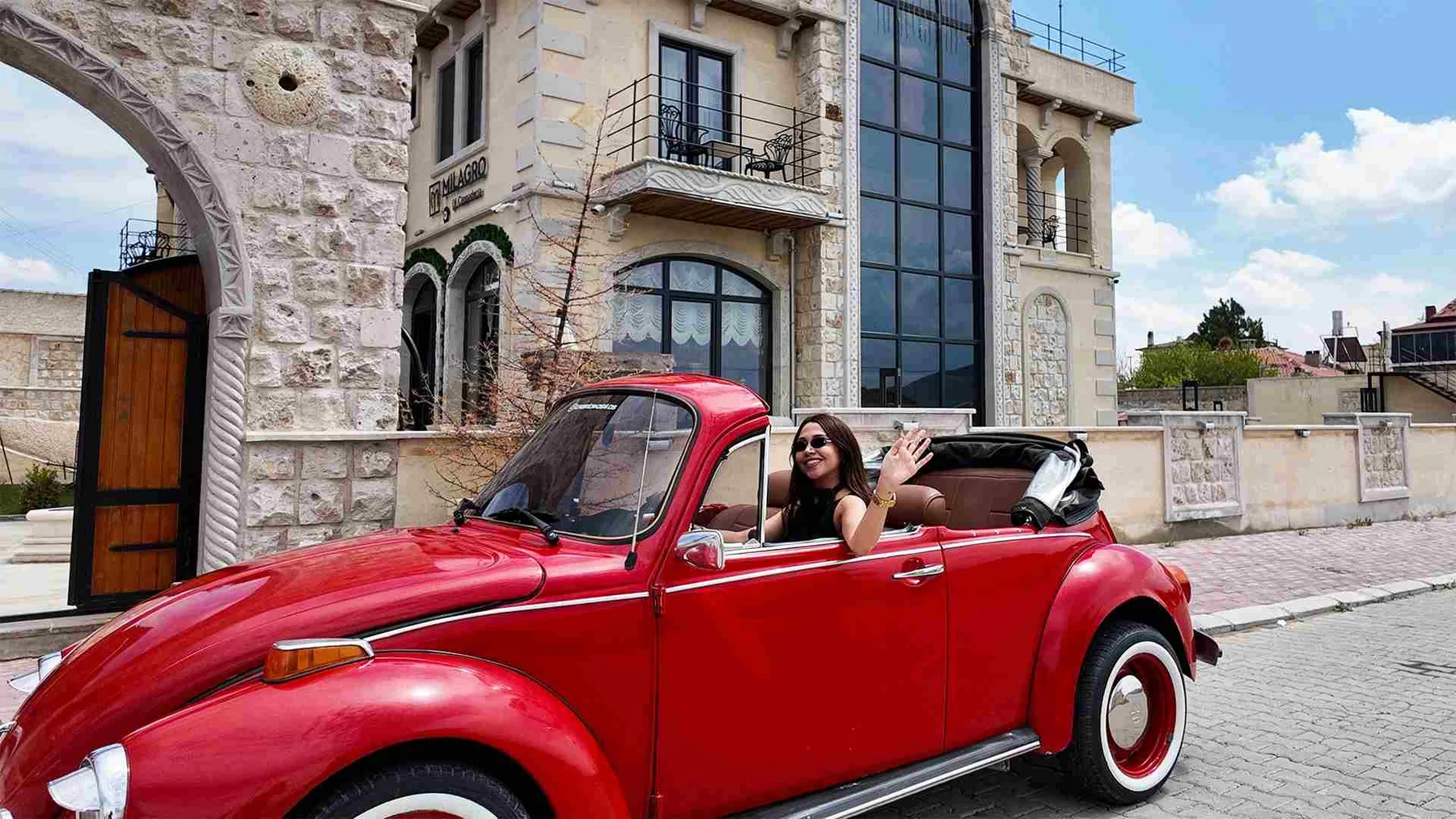 Stone hotel entrance and red classic car