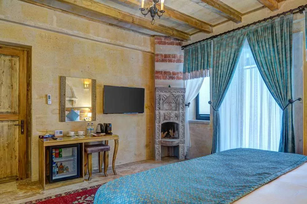 Interior de la suite Premium con cama, televisión y chimenea de piedra