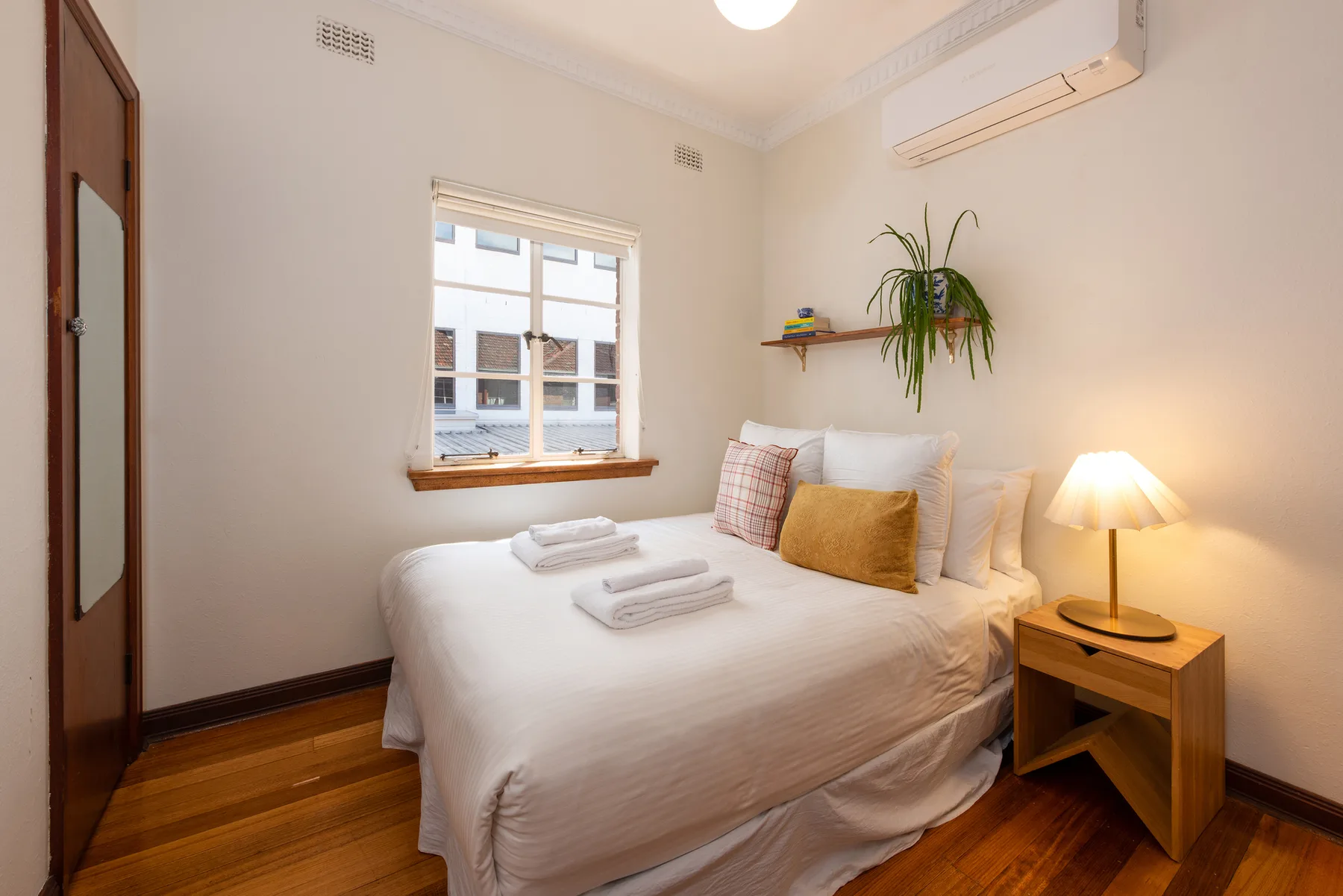 A bedroom with a neatly made bed and a bedside table.