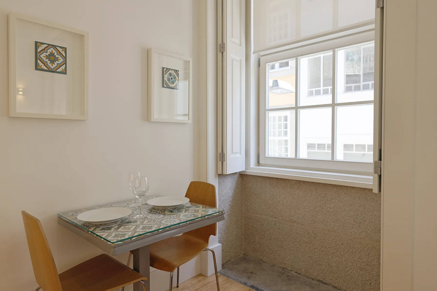 A small dining area with a table and chairs beside a large window.