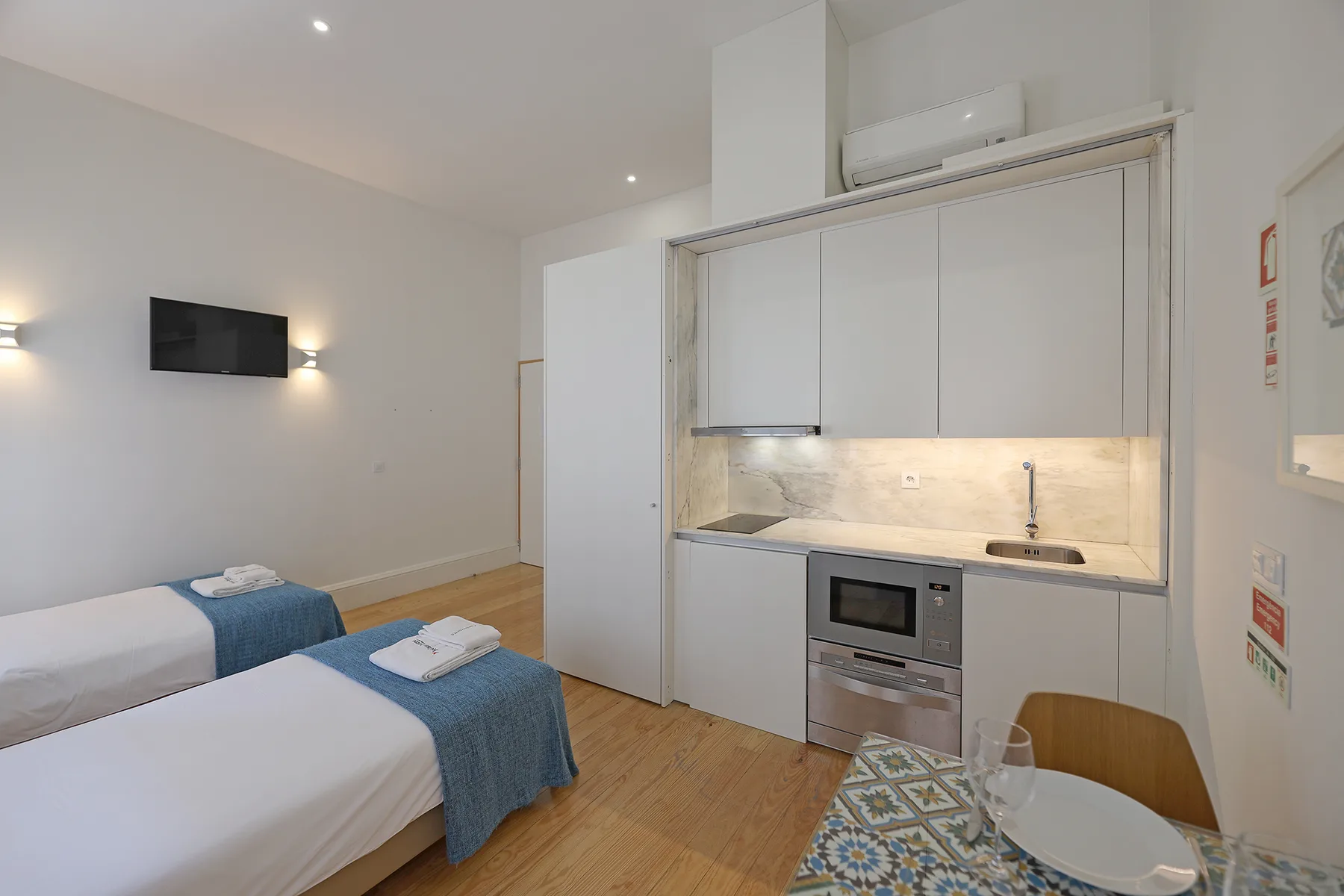 A studio room with two beds and a compact kitchen area.