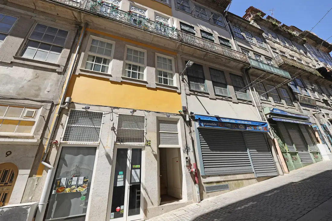 Street view of adjoining buildings with storefronts and upper-floor windows.